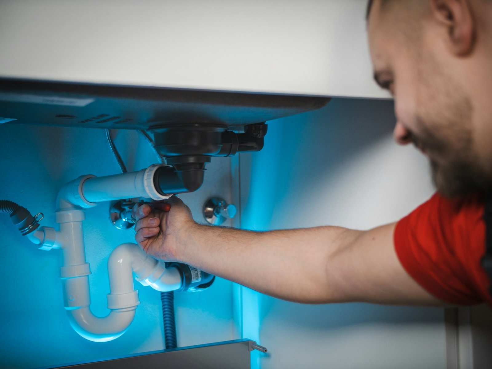 Plumber working on pipes inside a wall
